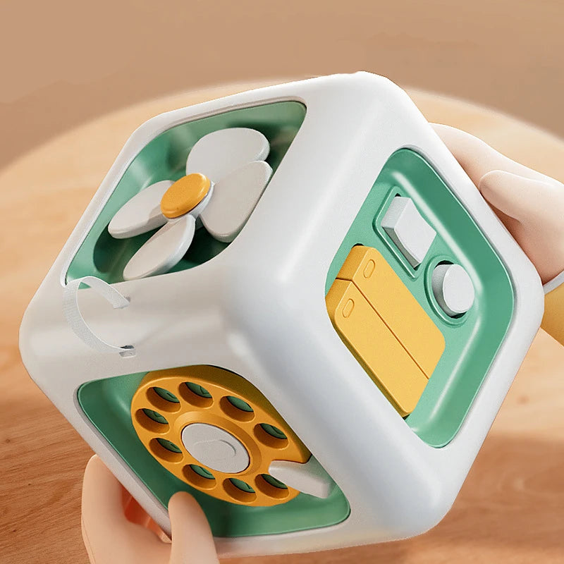 Toddler exploring a busy cube with tactile and interactive components