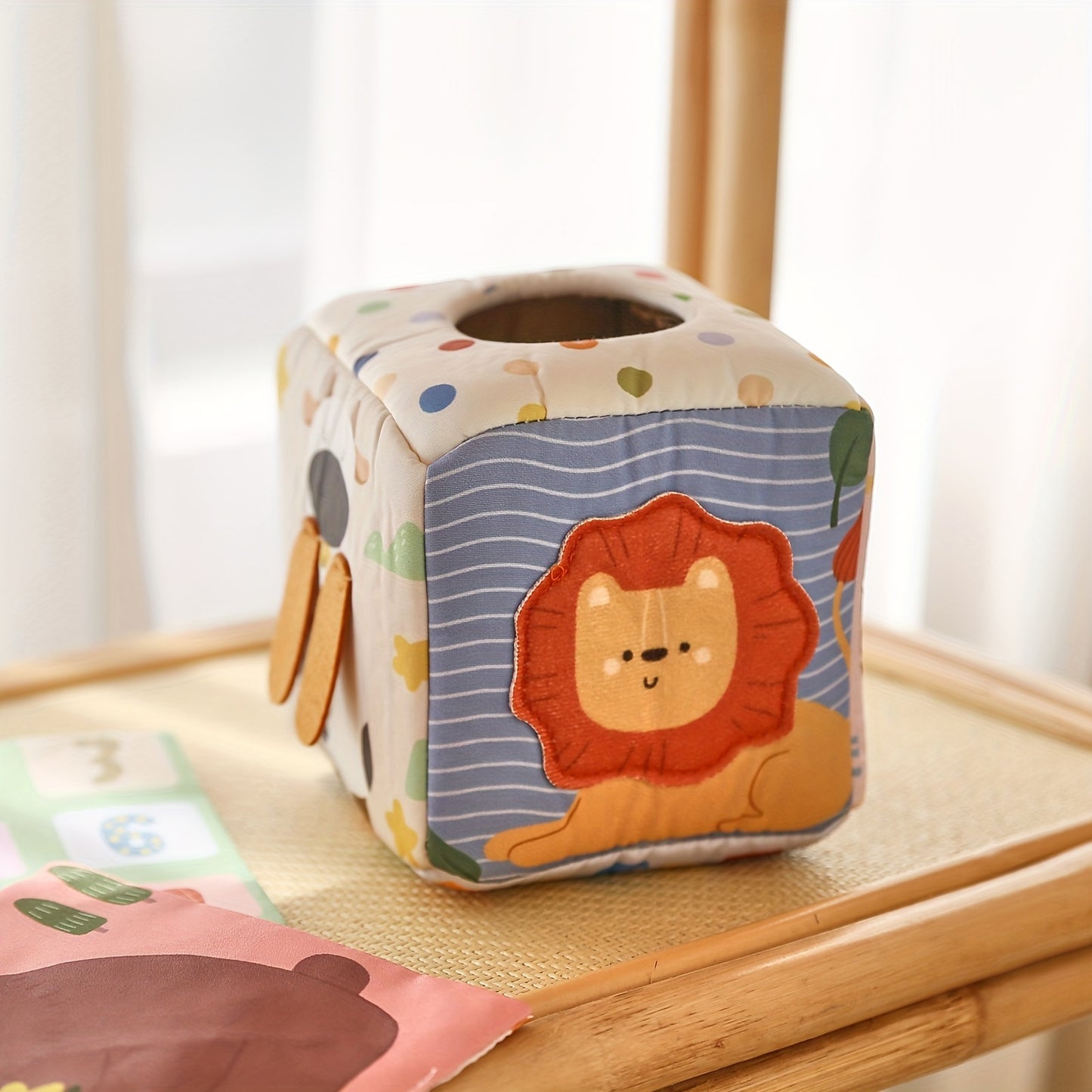 Infant developmental toy with a tissue play box filled with soft tissues for sensory and motor skill growth.