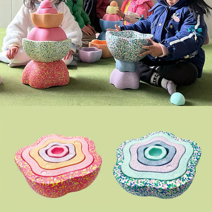 Children playing with colorful balance stones arranged in a pyramid structure for creative stacking