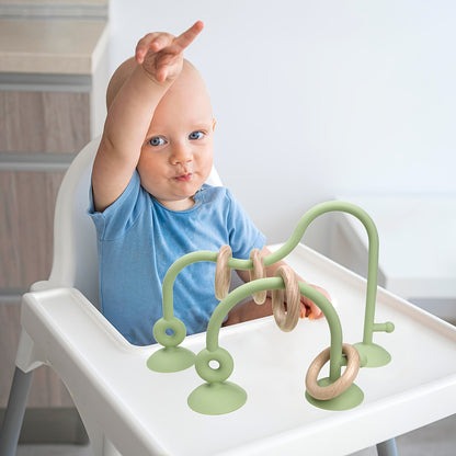 Baby playing with wooden ring along mint maze toy’s soft silicone path