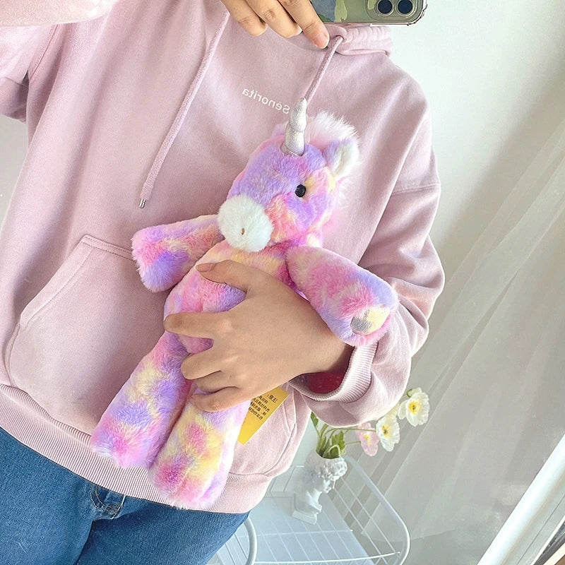 Person holding a colorful unicorn plush toy in front of a pink hoodie.