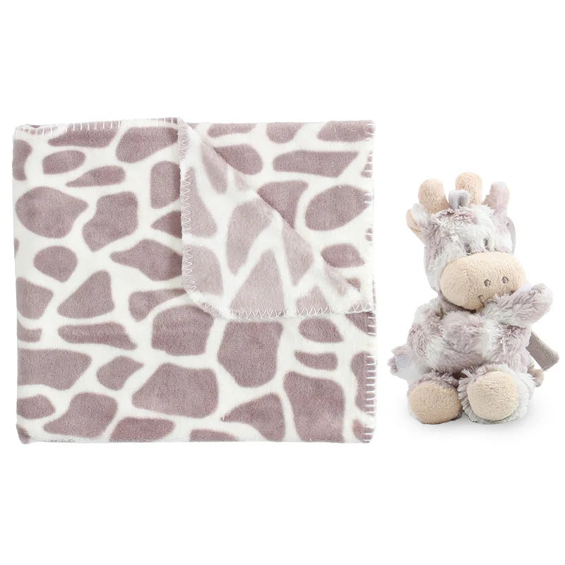 Giraffe-patterned blanket and stuffed giraffe toy on a white background