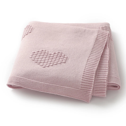 Pink knitted blanket with a heart design on a white background