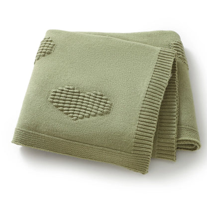Folded green blanket with a heart pattern on a white background