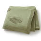 Folded green blanket with a heart pattern on a white background