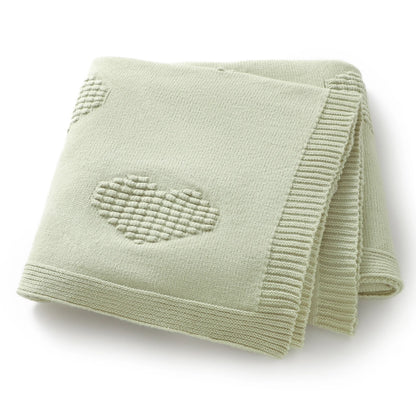 Light green knitted blanket with a heart design on a white background