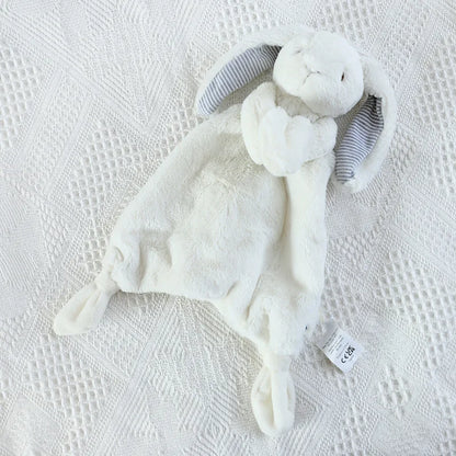 White plush toy with gray ears on a textured white surface