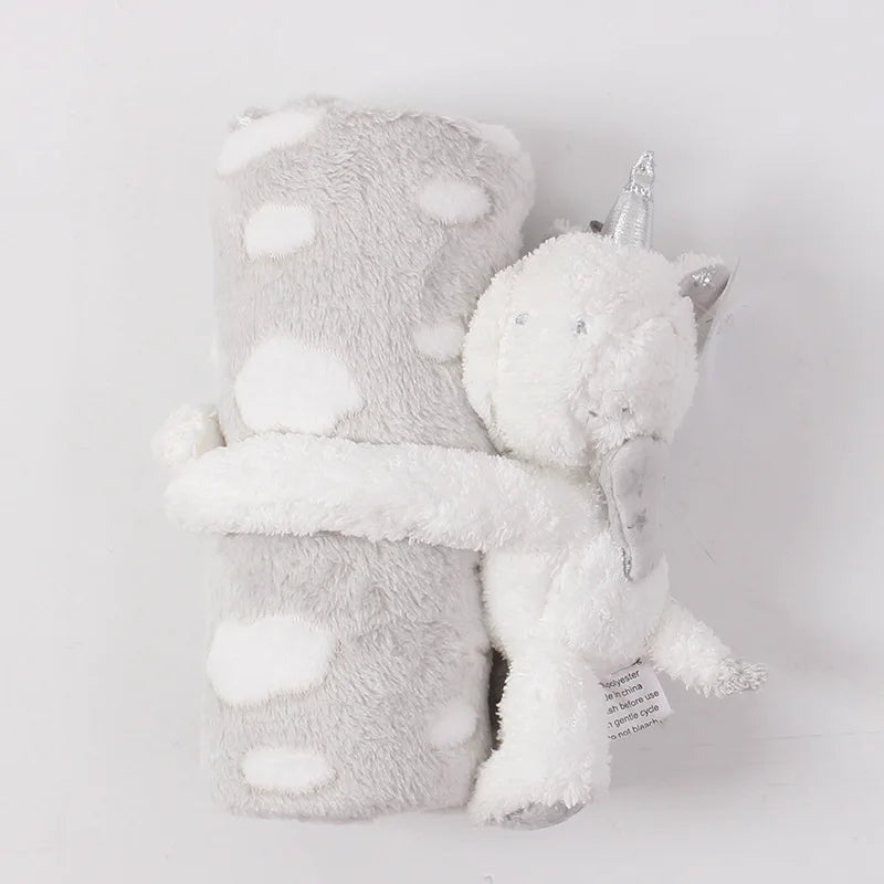 Plush toy with a unicorn horn and gray blanket on a light gray background