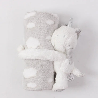 Plush toy with a unicorn horn and gray blanket on a light gray background