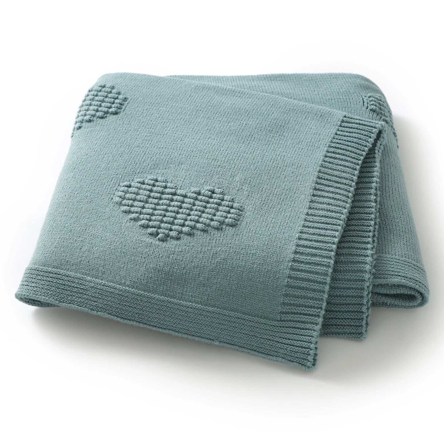 Folded teal / green knitted blanket with heart patterns on a white background