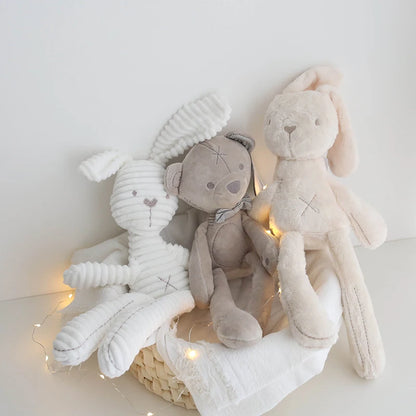 Three plush toys in a basket with string lights on a white background