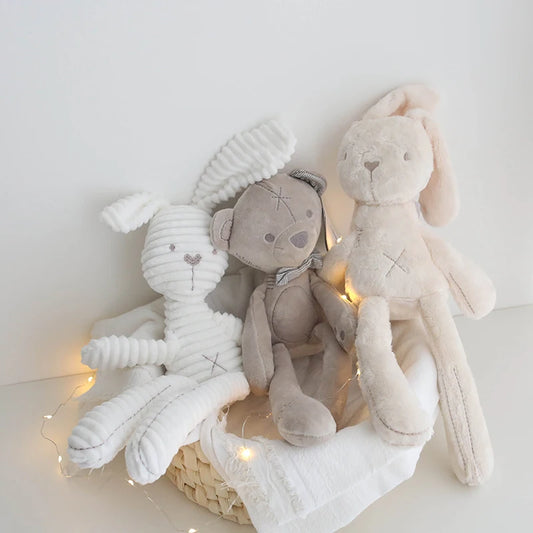 Three plush toys in a basket with string lights on a white background