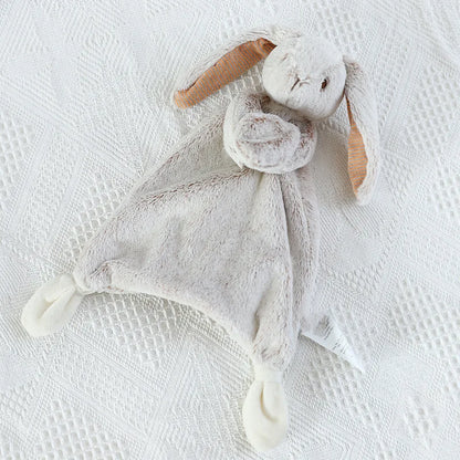 Grey plush bunny toy on a textured white surface