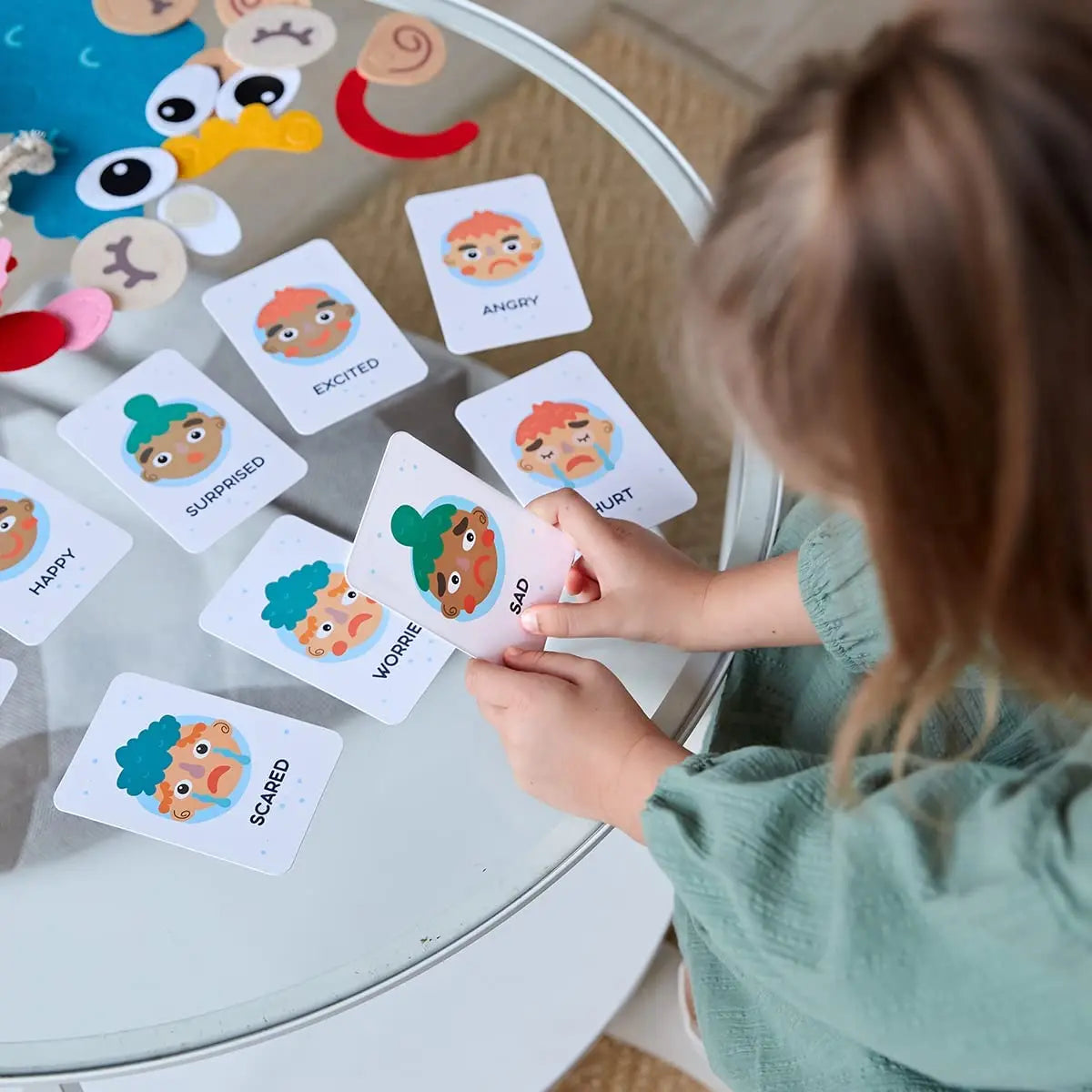 Child creating facial expressions on soft felt face for emotional learning