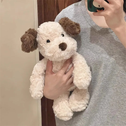 Person holding a small white dog plush toy with brown ears and nose.