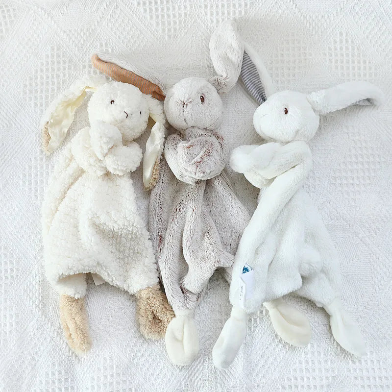 Three soft toy animals on a textured white surface