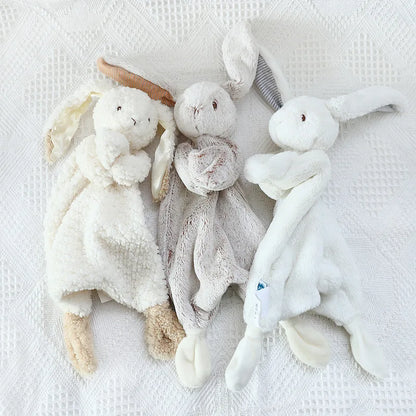 Three soft toy animals on a textured white surface