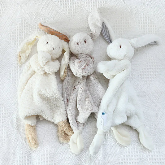 Three soft toy animals on a textured white surface