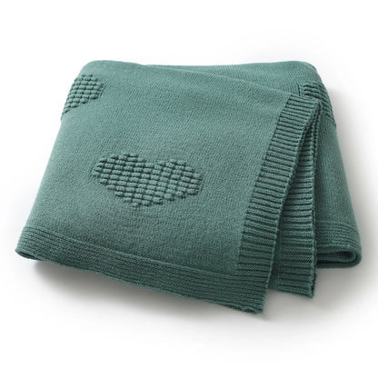 Green knitted blanket with heart patterns on a white background