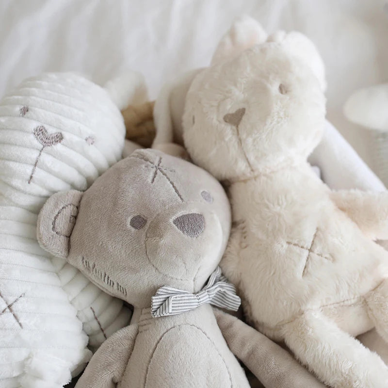 Three soft toys, including a bear and a ball, on a textured surface.
