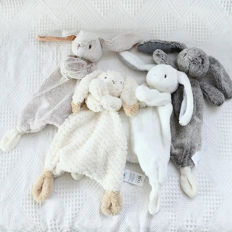Collection of soft toys laid down on a white blanket.