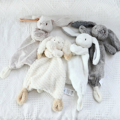 Collection of soft toys laid down on a white blanket.