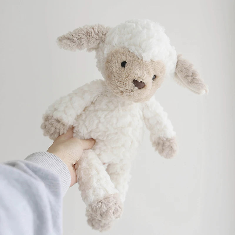 Stuffed lamb toy held by a hand against a plain background